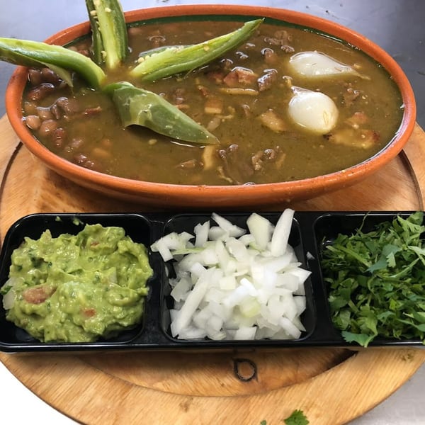 Mexican stew with jalapeños and onions, served with guacamole, diced onions, and cilantro.