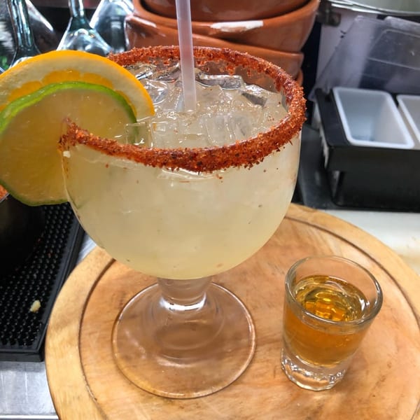 A Pika Tortas Ahogadas margarita with a chili-lime rim, citrus slices, and a tequila shot.